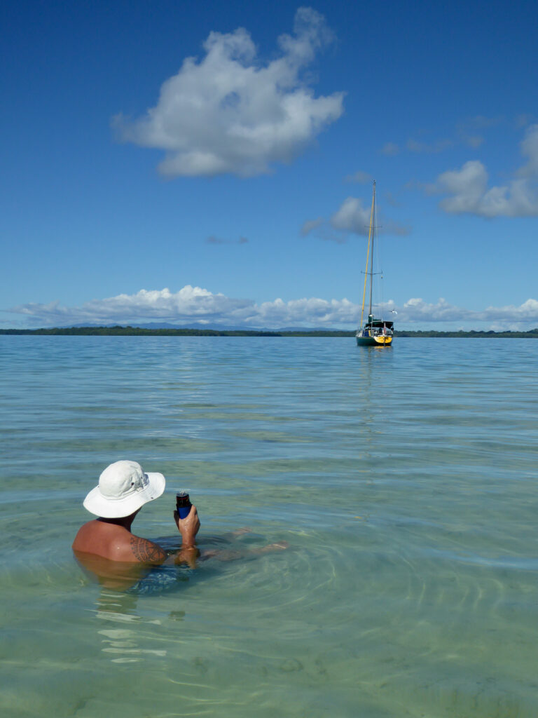 man in water looking at sailboat